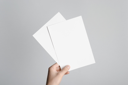 68188917-a5-flyer-invitation-mock-up-mains-mâles-tenant-des-flyers-vierges-sur-un-fond-gris-